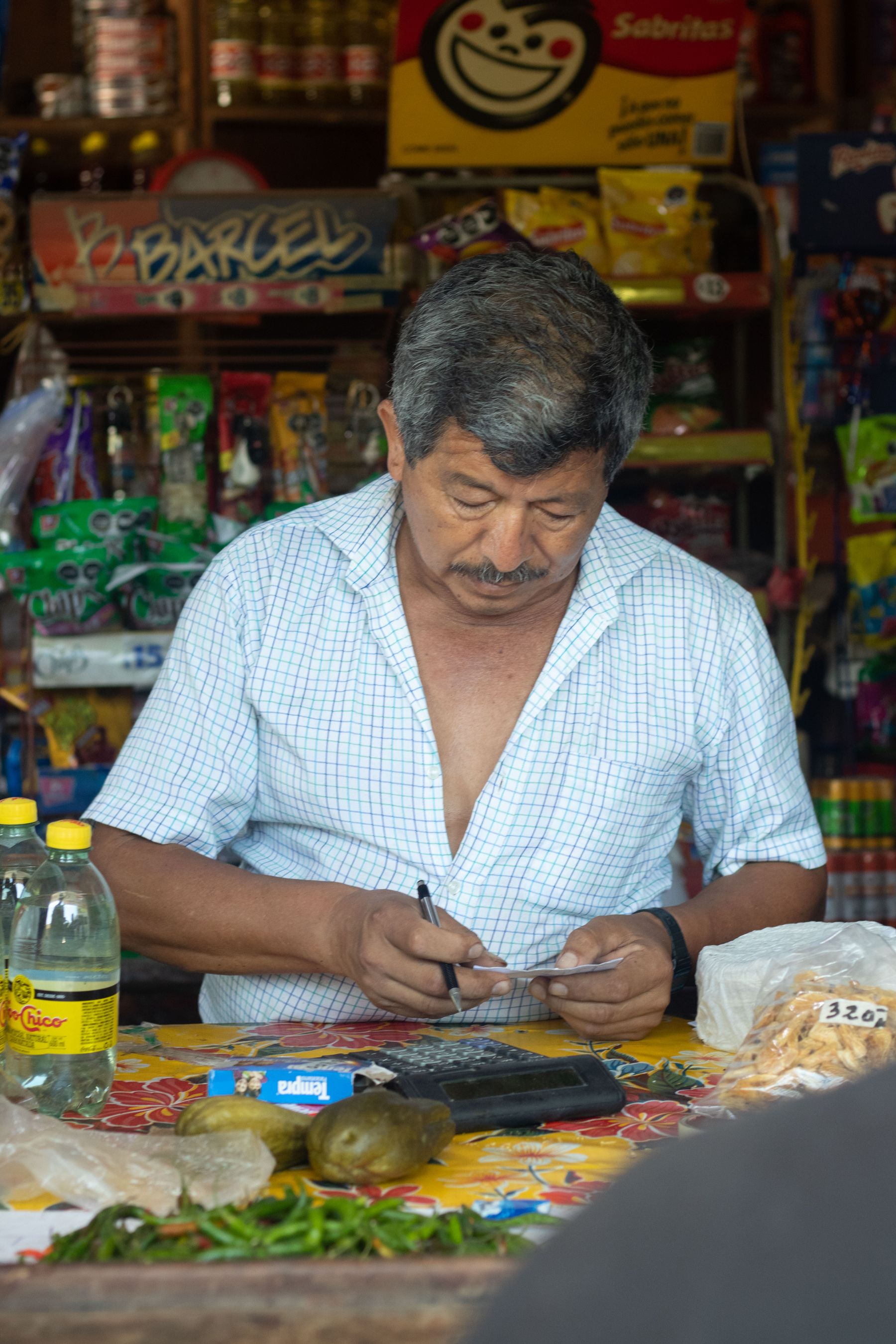 A neighborhood shopkeeper reviewing the day's records behind the counter