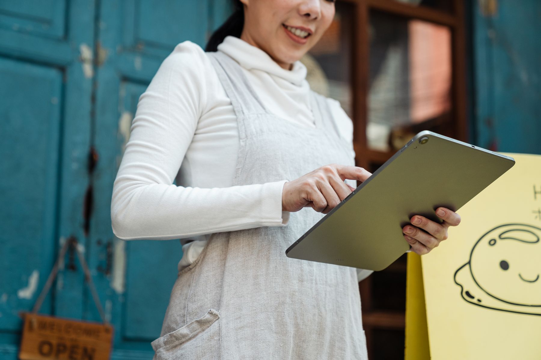 An independent shop owner using a tablet outside her storefront