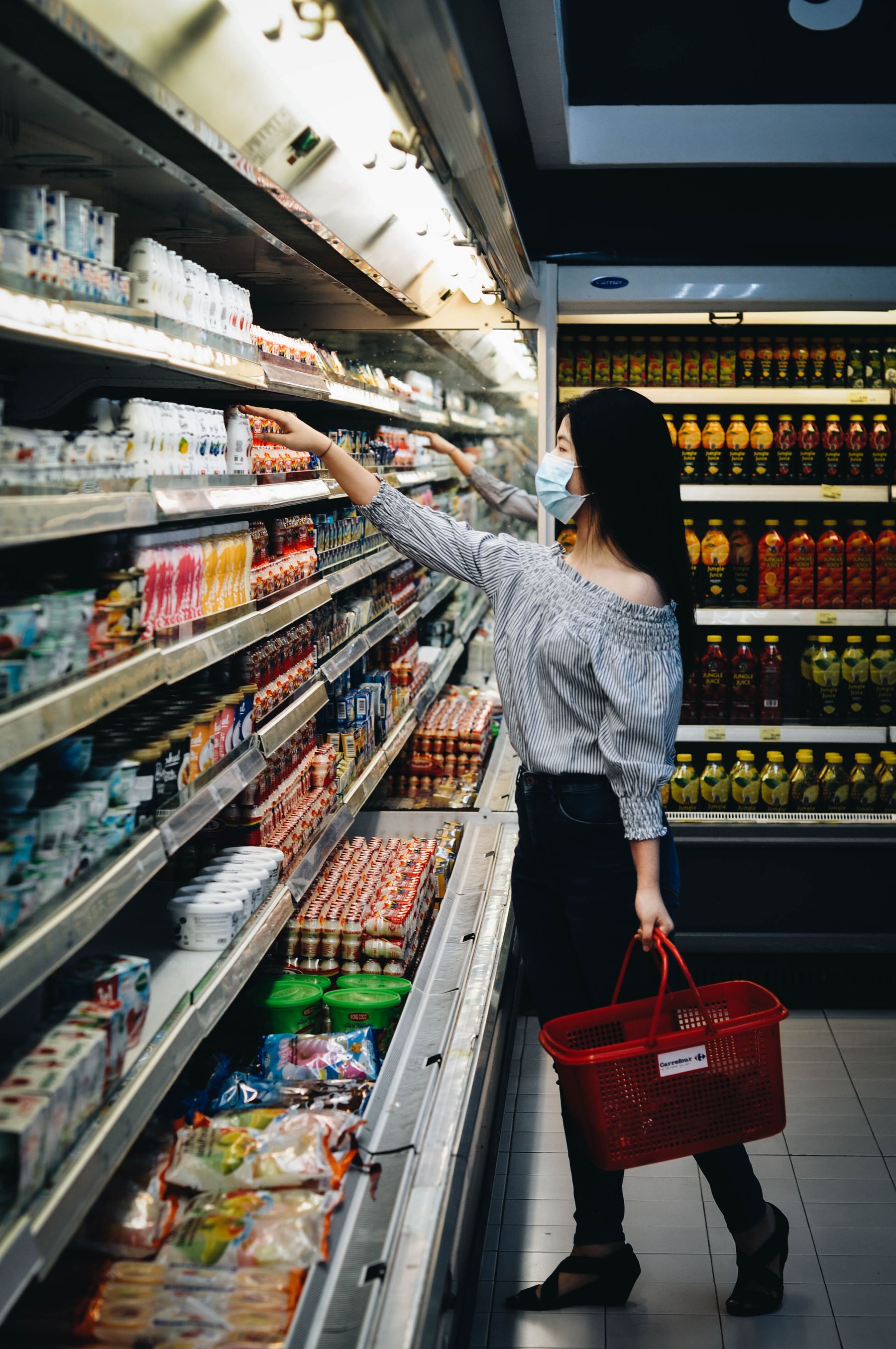A shopper reaching for a product in a grocery aisle