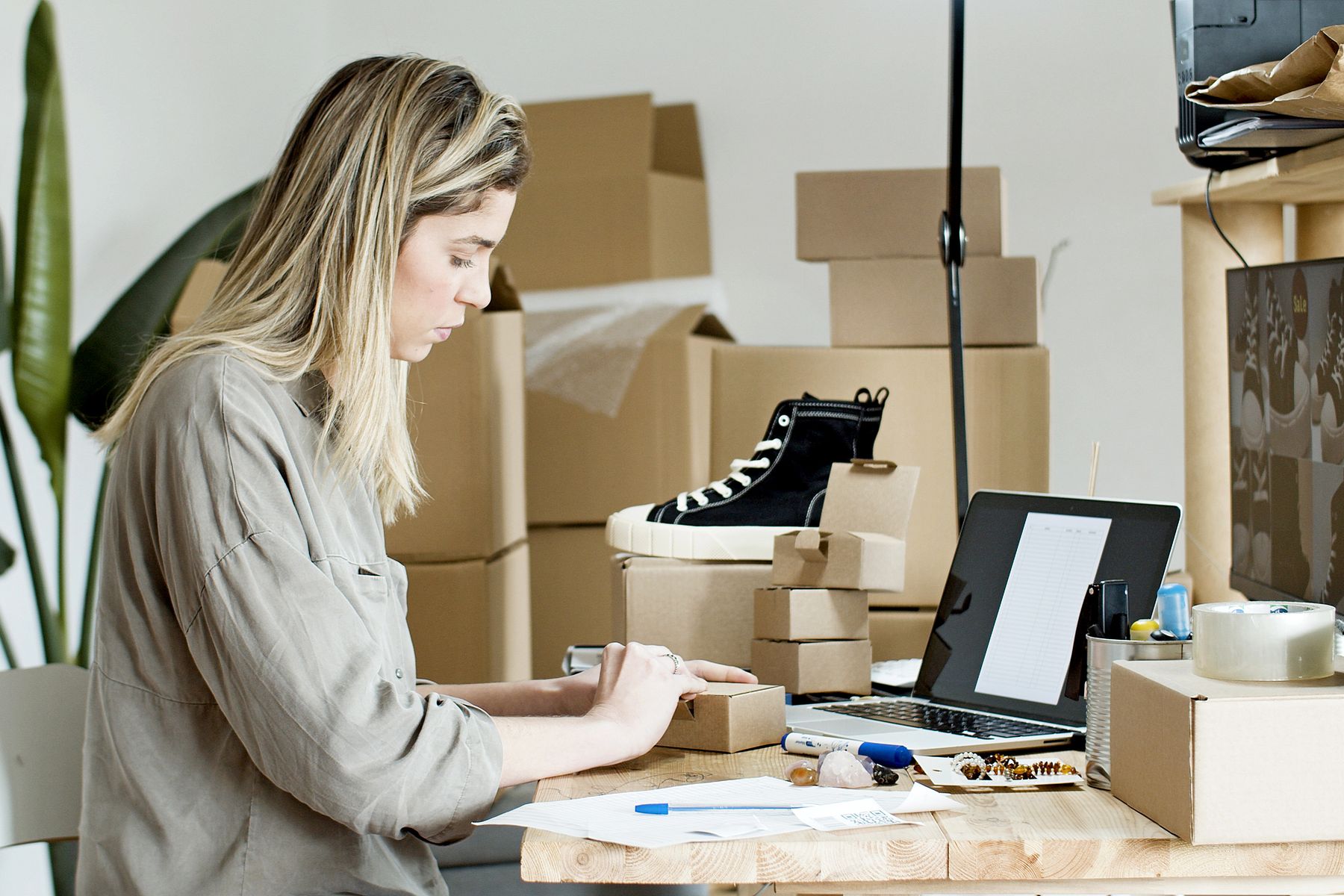 An independent retailer packing an online order beside shipping boxes