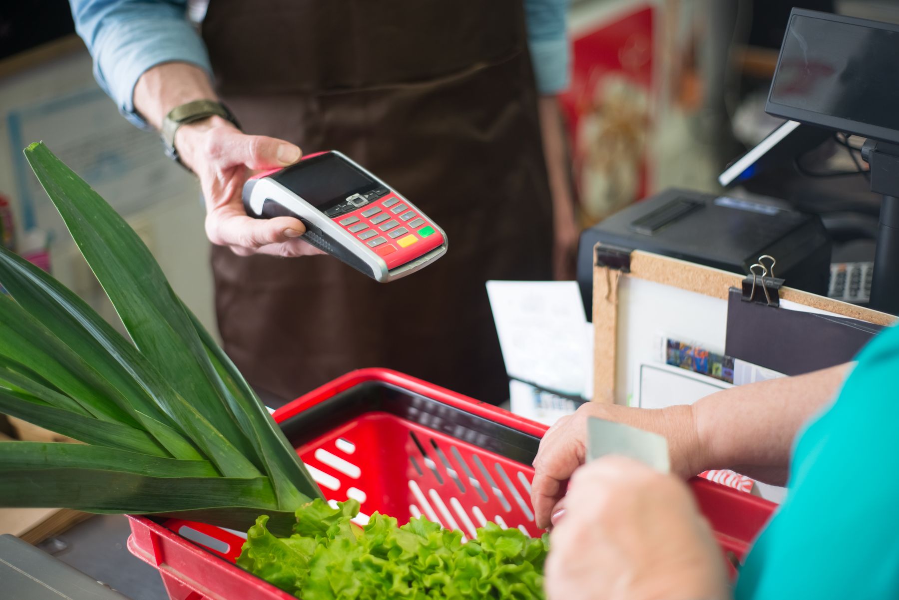 A customer completing a contactless payment at a grocery counter