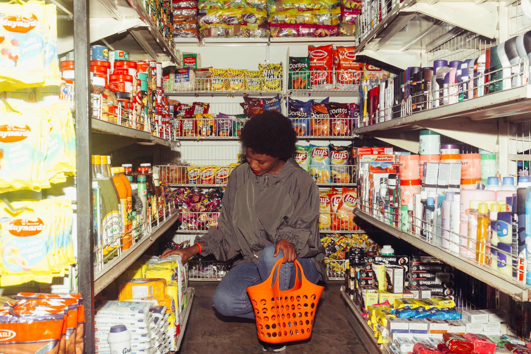 A shopper selecting products in a neighborhood grocery aisle