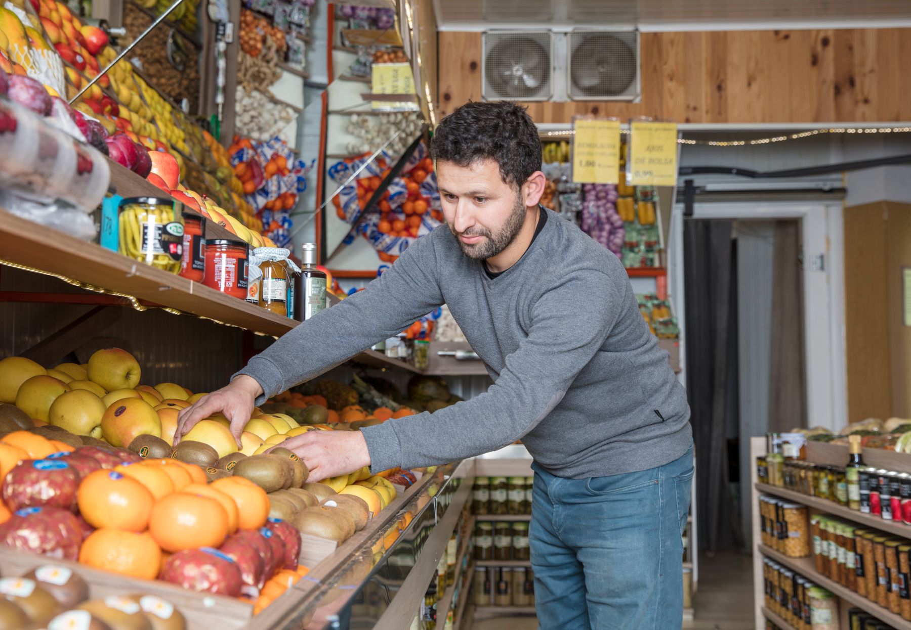 A grocery worker arranging fresh fruit on a store display
